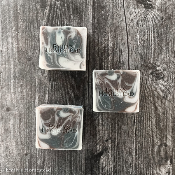 Brown, white and black swirled men's soap sitting on weathered wood tabletop.
