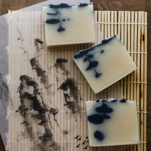Three bars of soap with black design on a textured surface