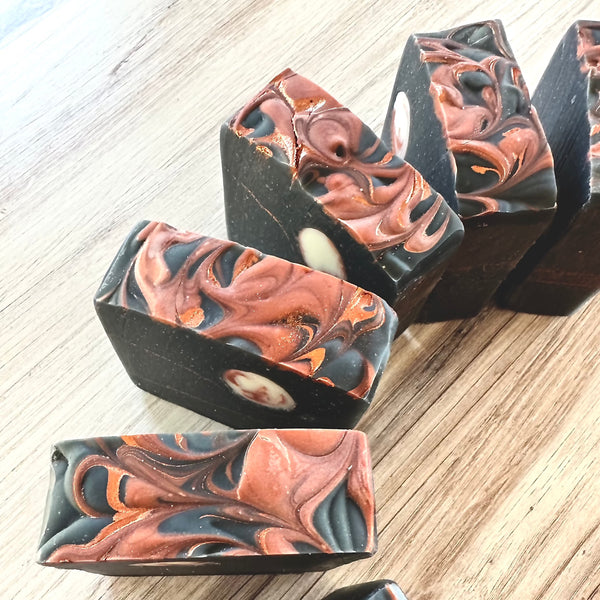 Activated Charcoal soap that is a black bar with a beautiful bronze swirl on top.  This bar also has a white and bronze swirled moon embed and is fragranced with cinnamon, apple, pumpkin and pine.
