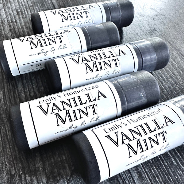 Four lip balm tubes labeled 'Vanilla Mint' on a wooden surface.