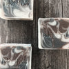 Brown, white and black swirled men's soap sitting on weathered wood tabletop. Closeup.